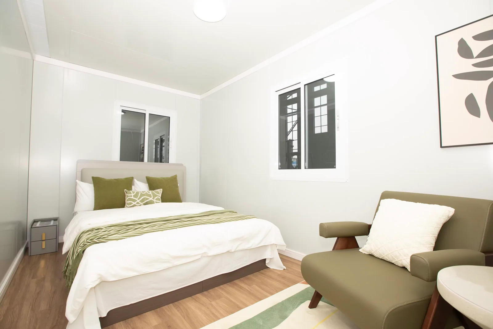Bright Eco Portables bedroom with a double bed, timber-look flooring, and an upholstered chair
