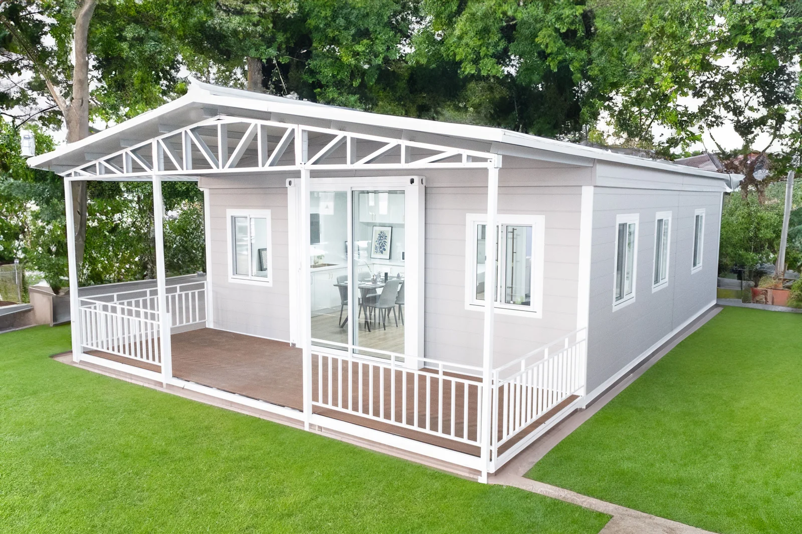 Light-grey Eco Portables home in daylight with a covered timber deck, white railings, and sliding glass doors